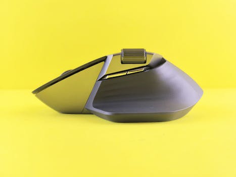 Side view of a sleek ergonomic wireless mouse set against a bold yellow backdrop, highlighting modern design and functionality.