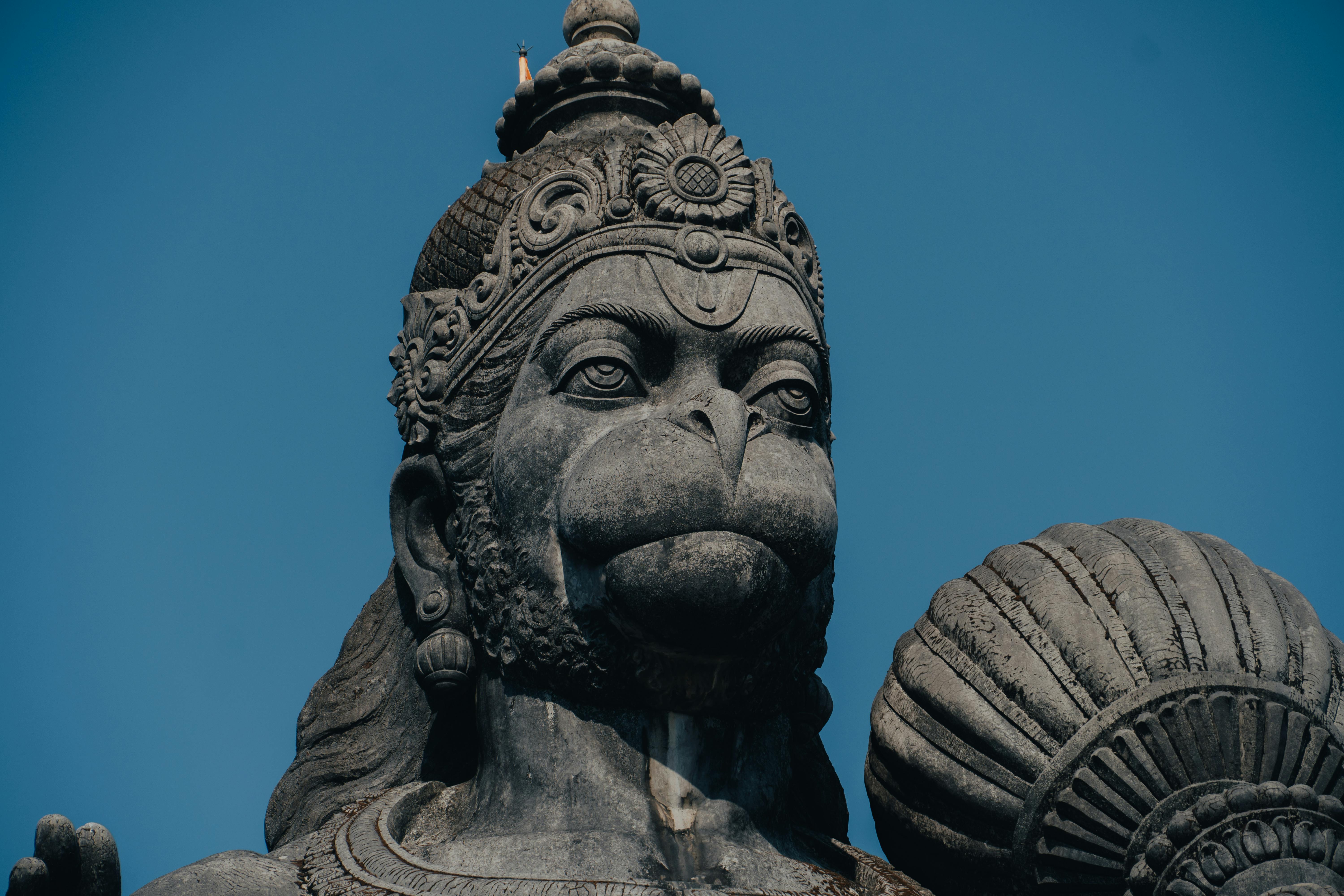 Captivating close-up of a stone Hanuman statue, a revered figure in Hinduism, under a blue sky in Bengaluru, India.