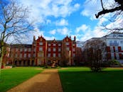 一座宏伟的红砖豪宅，在阳光照耀下，映衬着充满活力的蓝天和郁郁葱葱的花园