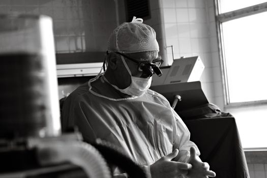 A surgeon in a surgical gown and mask prepares for an operation in a hospital setting.