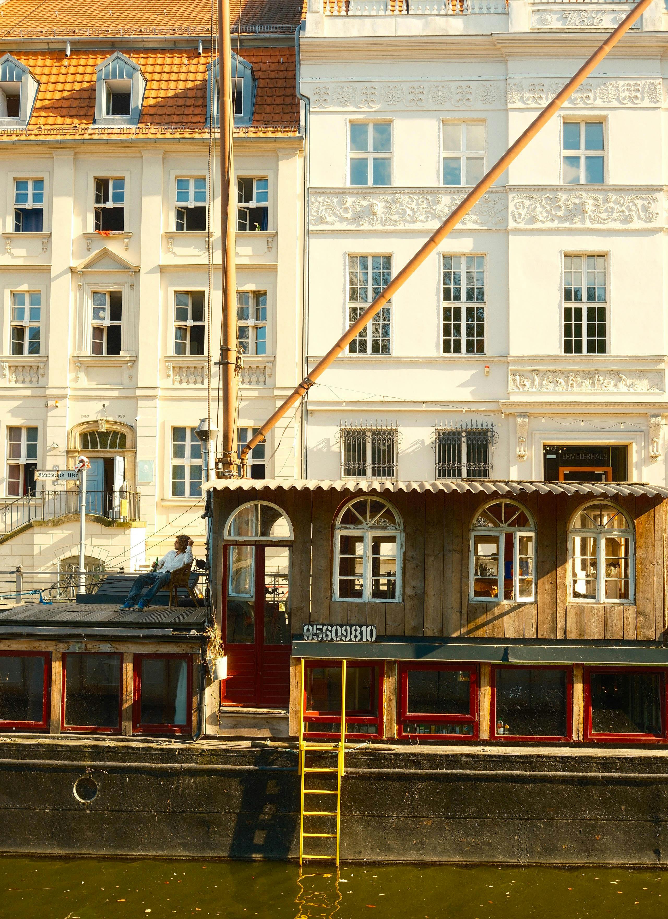 Charming houseboat moored against historic architecture in Berlin, Germany, during day.