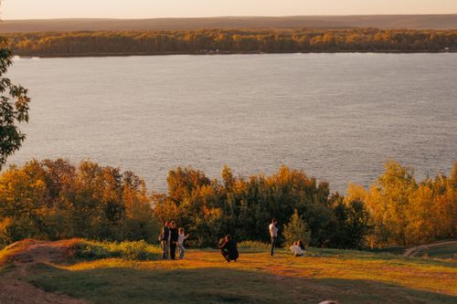 Free A small group of people enjoy a beautiful sunset view over a river surrounded by lush trees. Stock Photo