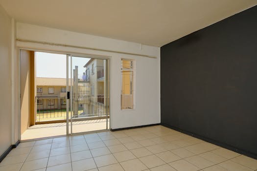 Bright interior space with tiled flooring and balcony view, ideal for real estate listings.