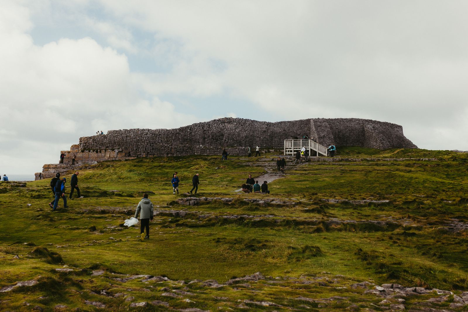 Tourists exploring Dun Aonghasa with views of rugged landscapes on Inis Mór, Ireland