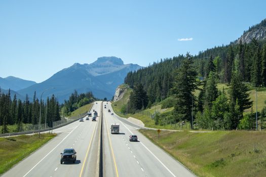 A picturesque highway scene in Banff National Park with mountains and lush greenery.