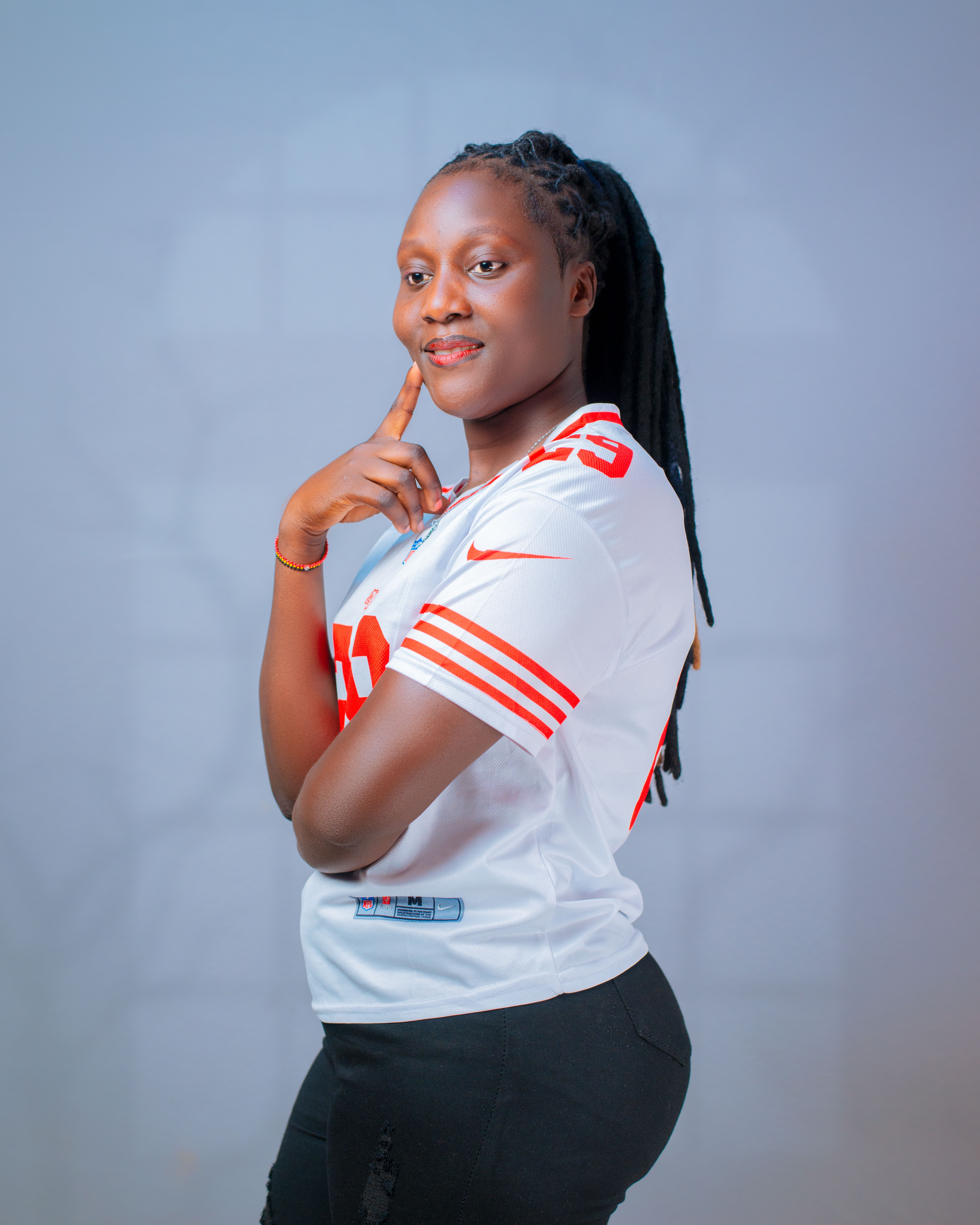Portrait of a smiling young woman wearing a sports jersey, posing with confidence indoors.