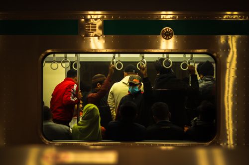 Free A view inside a crowded subway train with diverse passengers, captured at night. Stock Photo