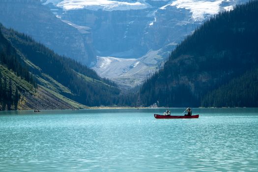 Two people canoeing on the turquoise waters of Lake Louise with stunning mountain backdrop.