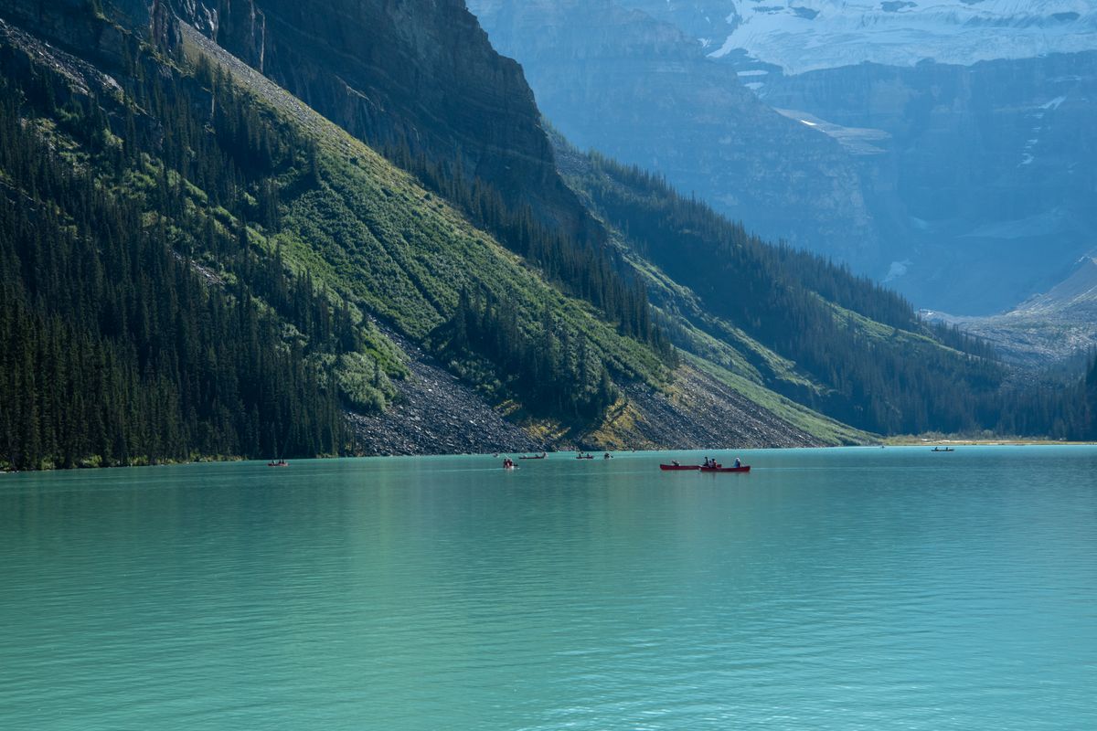 Canoes on turquoise mountain water surrounded by peaks