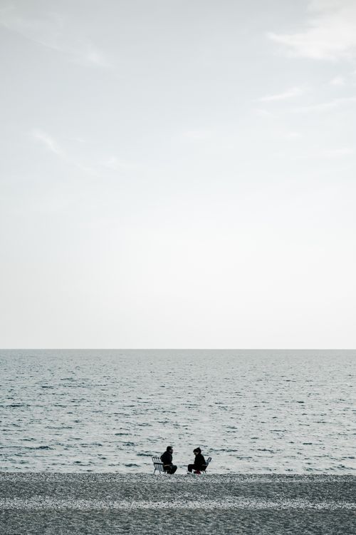 Free Two people relaxing on a serene beach, capturing peaceful solitude by the sea. Stock Photo