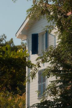 Aesthetic white house with blue shutters amidst greenery on Heybeliada, Istanbul.