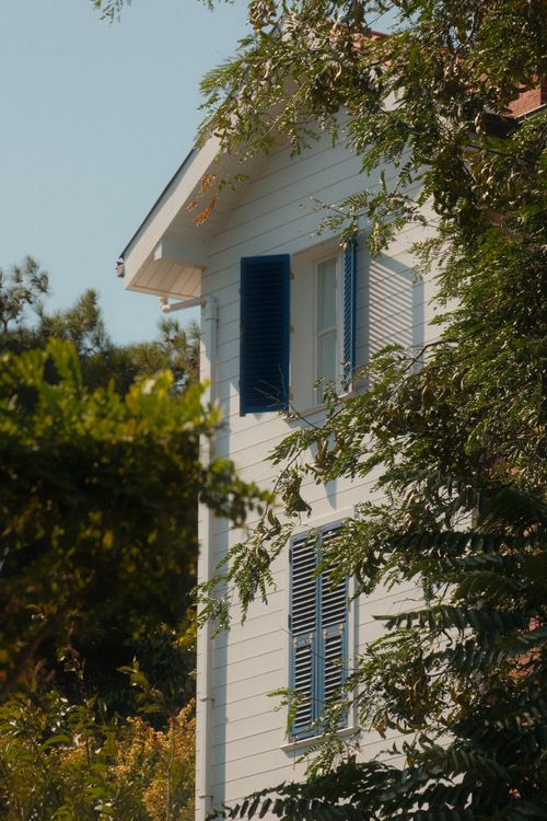 Free Aesthetic white house with blue shutters amidst greenery on Heybeliada, Istanbul. Stock Photo