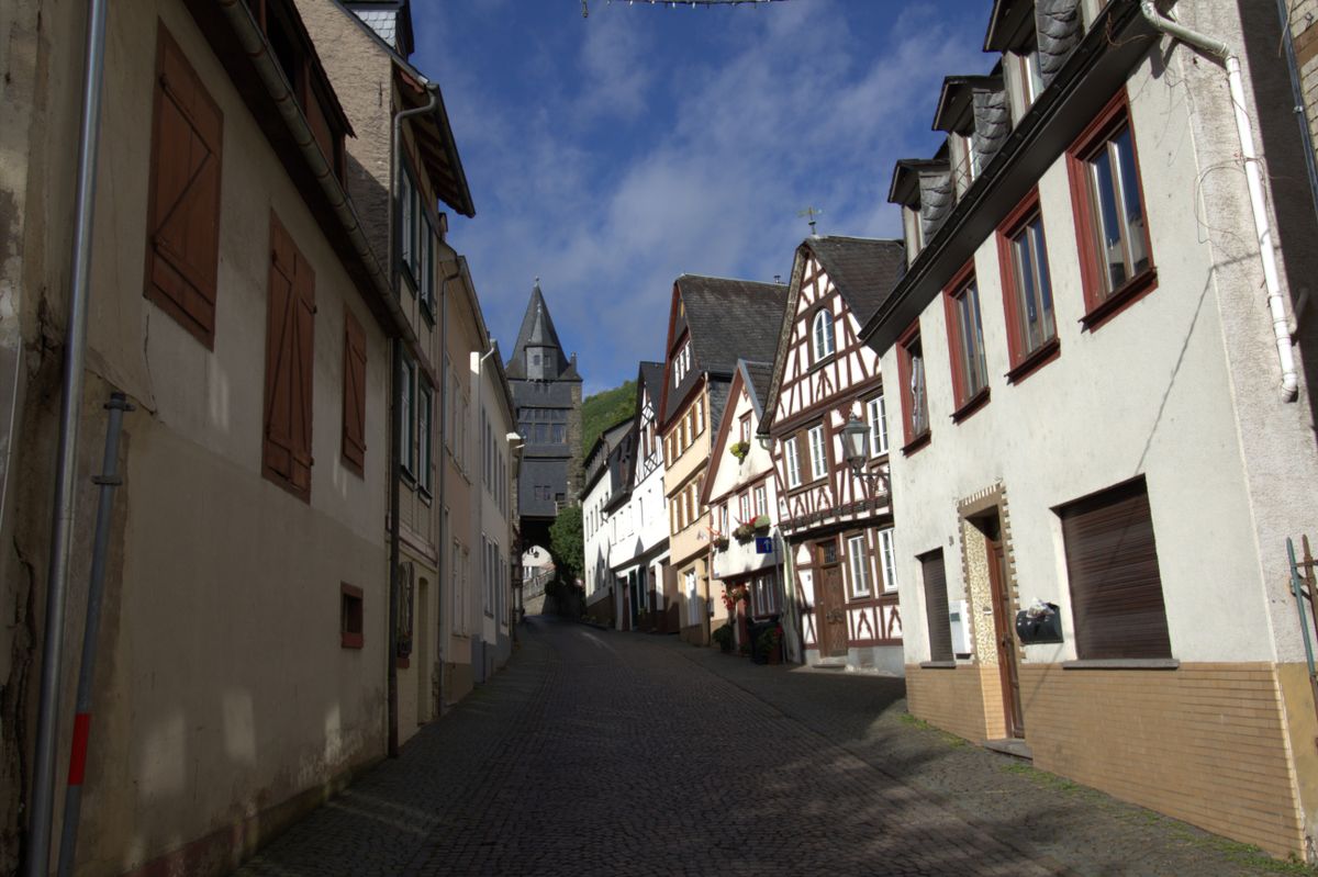 A cobbled sloping lane lined with half-timbered and plastered houses, with a gate tower at the end
