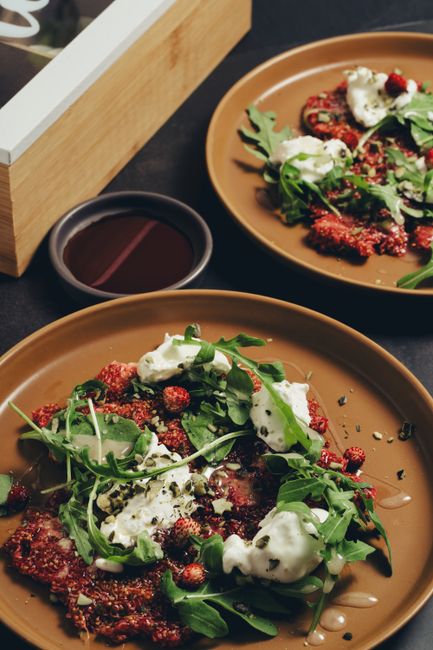 A savory arugula and beet salad topped with cheese on ceramic plates.
