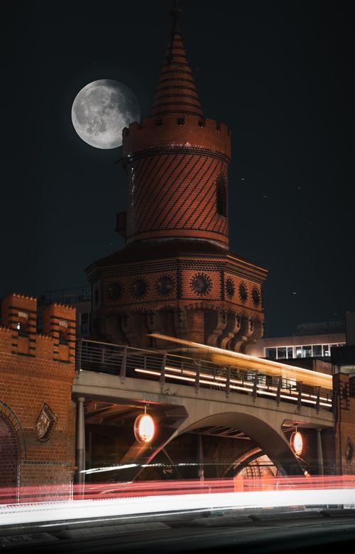 Free Night view of Oberbaum Bridge, Berlin, with bright moon and light trails from passing train. Stock Photo