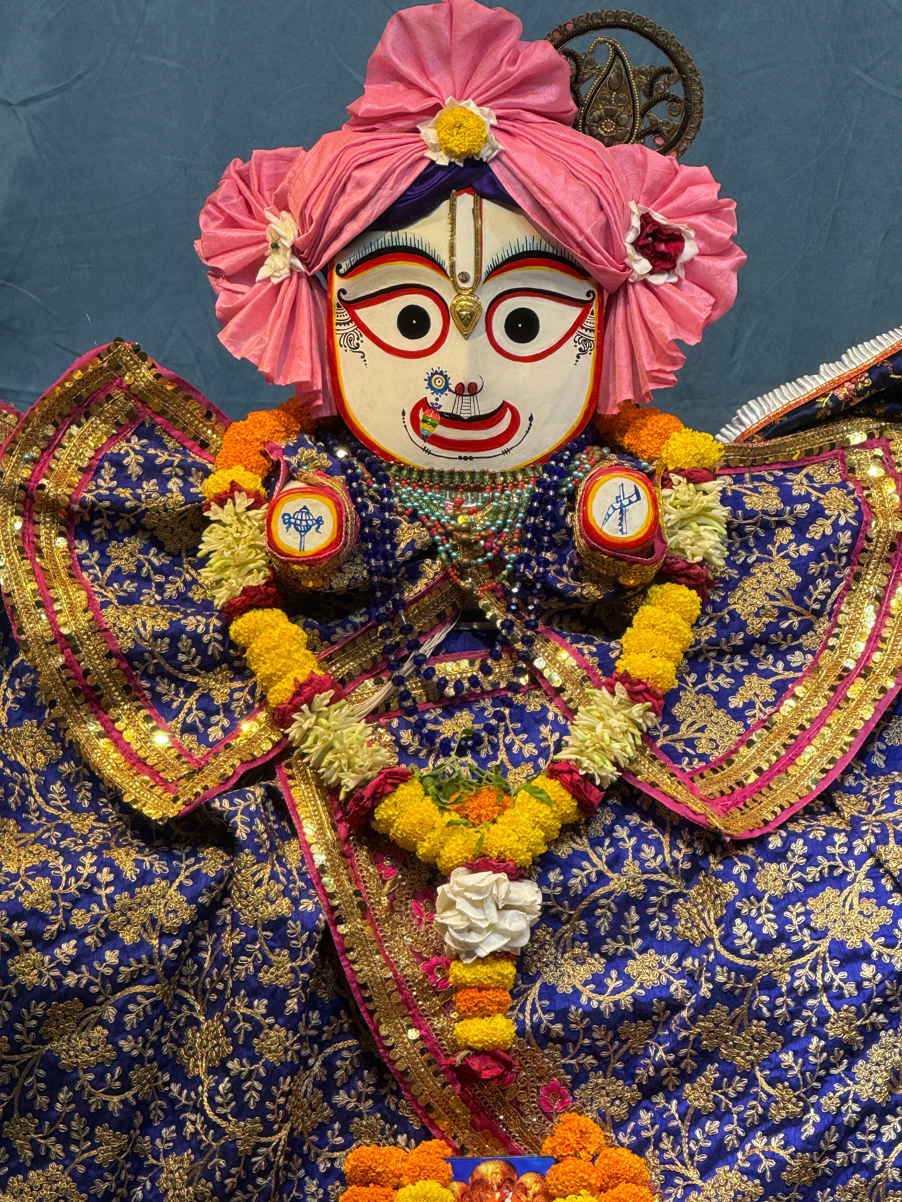Colorful depiction of a Hindu deity adorned with traditional garments and floral decorations.