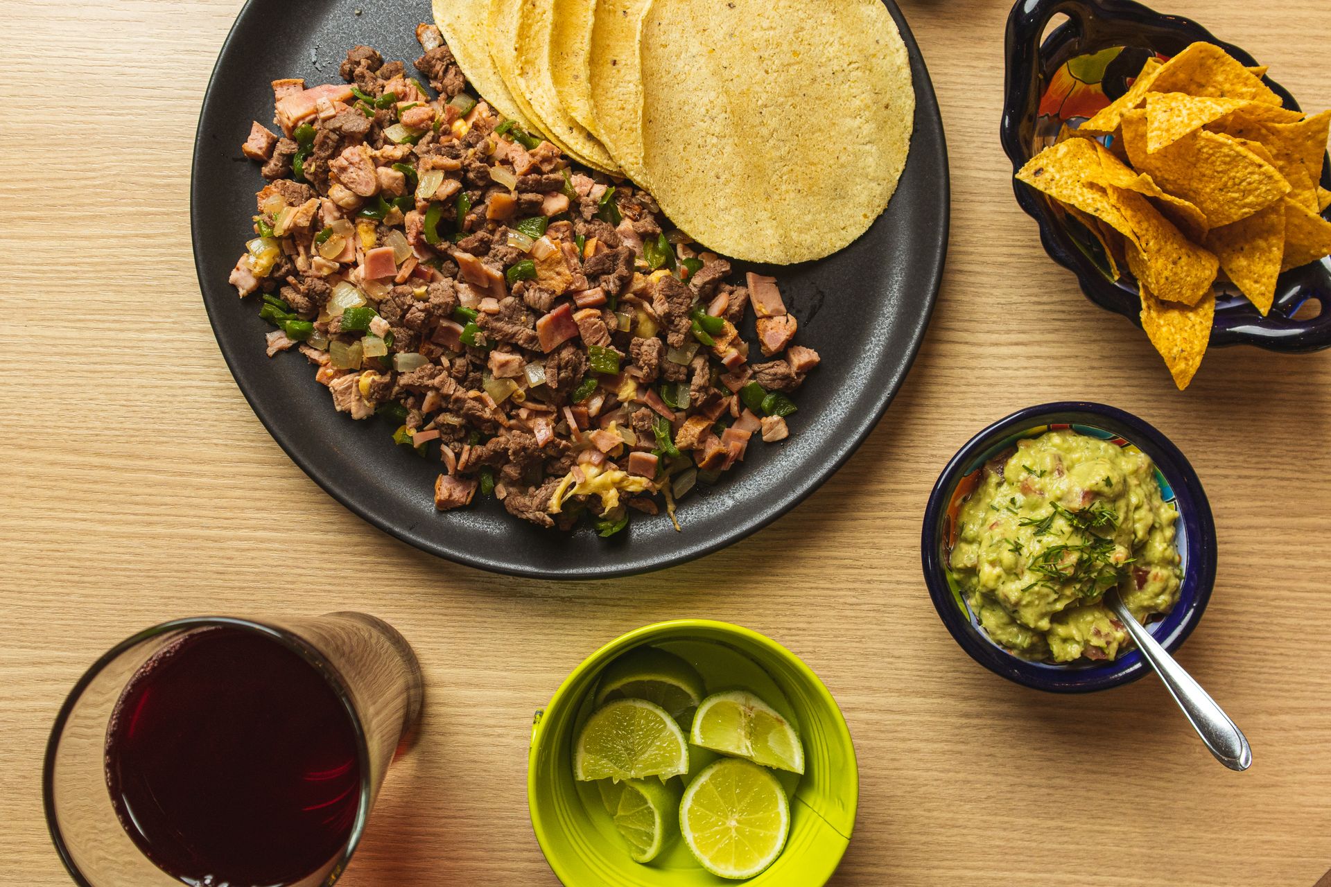 Delicious Mexican taco platter with fresh guacamole, tortilla chips and lime wedges.