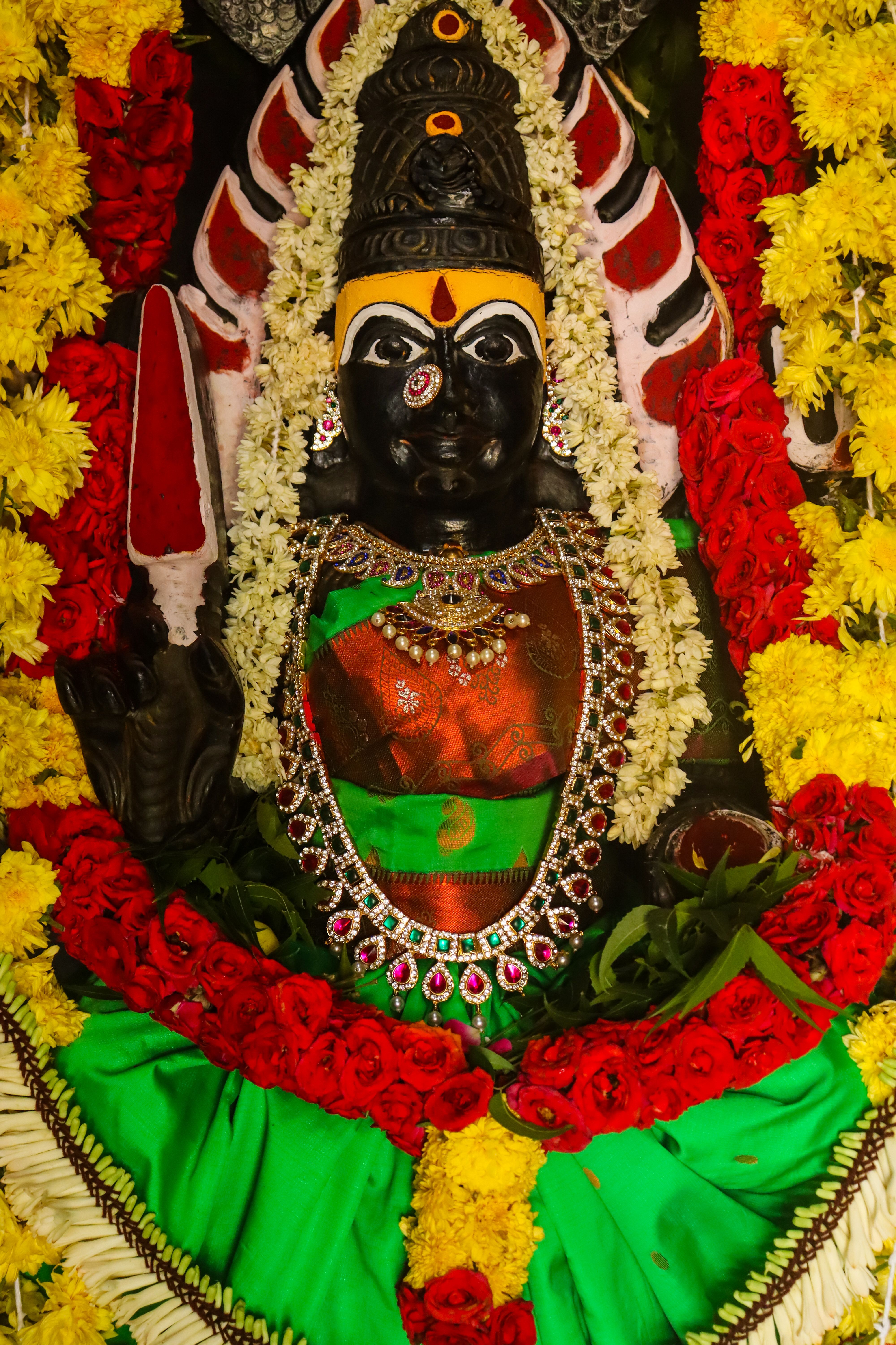 A beautifully adorned Hindu deity statue with colorful garlands symbolizing spiritual devotion.