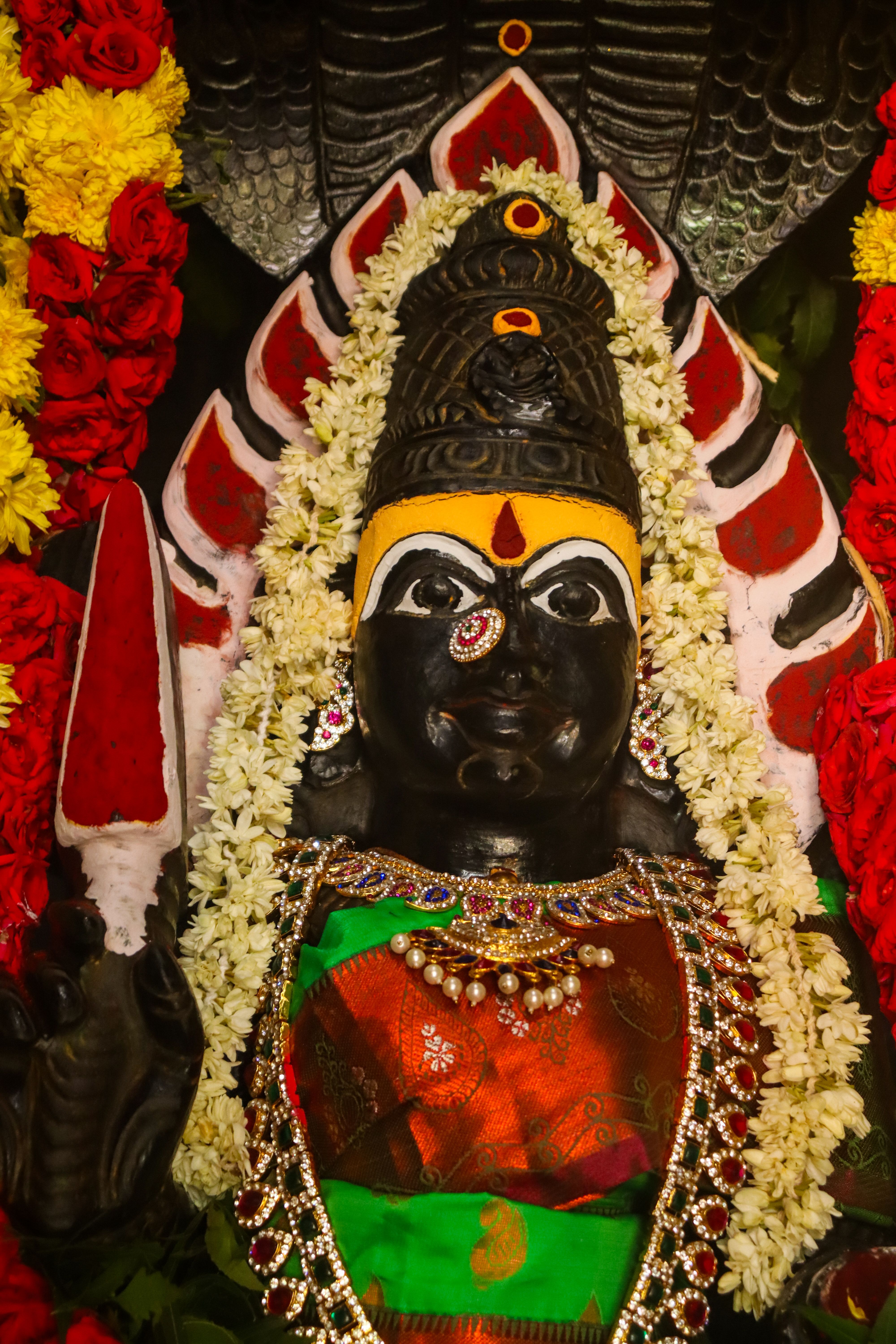 Close-up of a richly adorned Hindu goddess statue decorated with vibrant flowers.