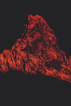 在黑色背景的映衬下，红色照明的山峰轮廓引人注目，唤起戏剧性与神秘感