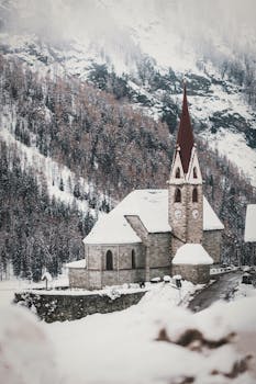 这座风景如画的教堂坐落在白雪覆盖的山地景观中，是冬季主题的理想选择