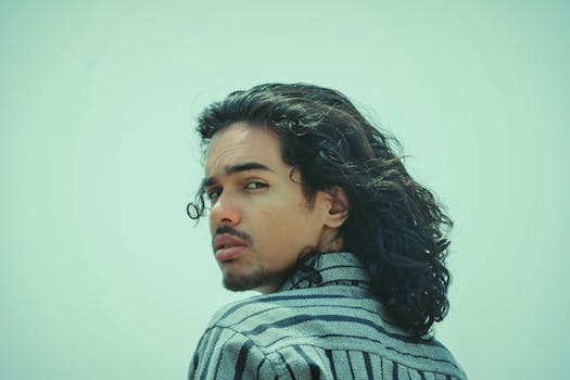 Portrait of a young man with long curly hair looking over his shoulder, outdoors in India.