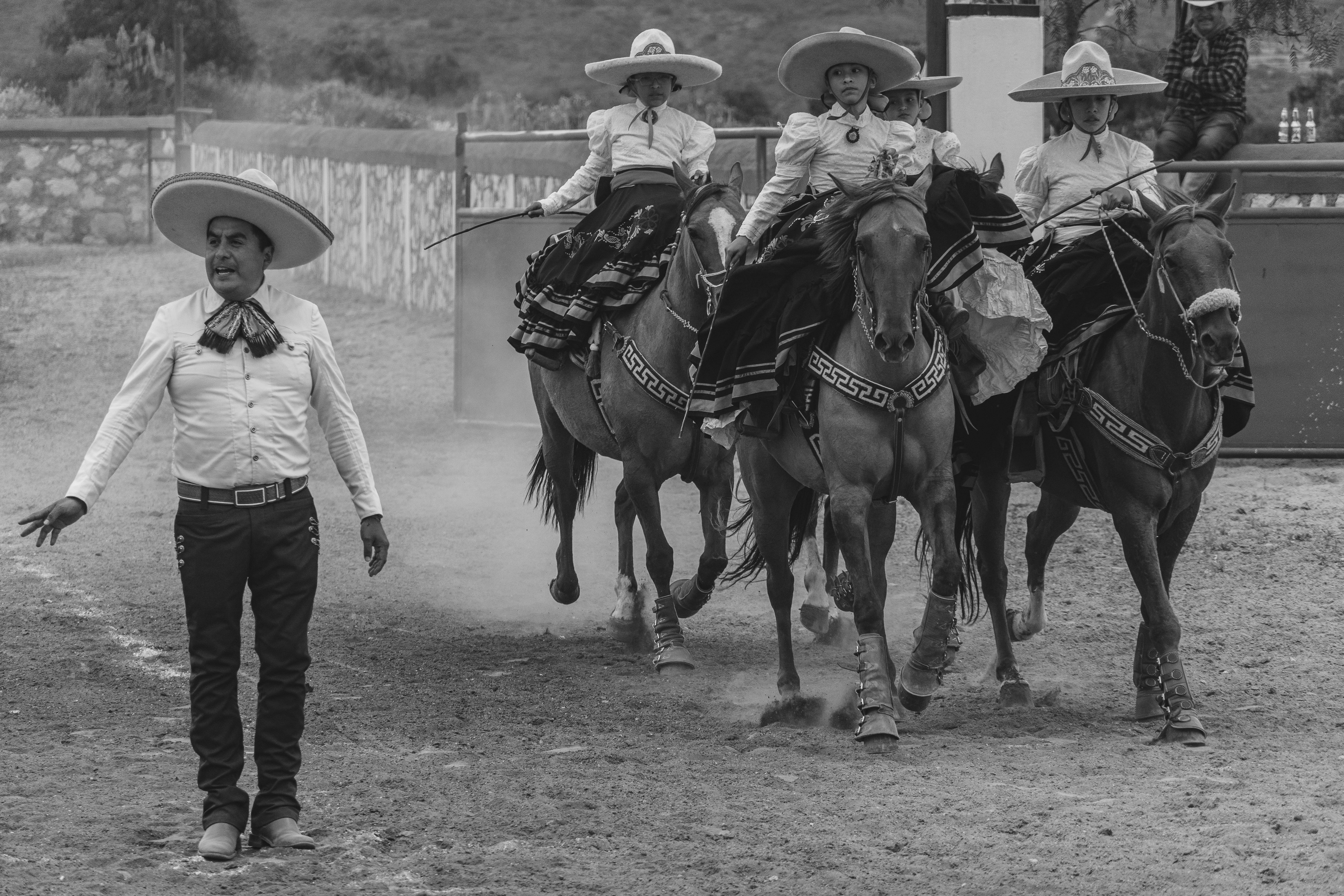 Black and white photo of charros on horses during a cultural event in San Juan Tizahuapan, Mexico.
