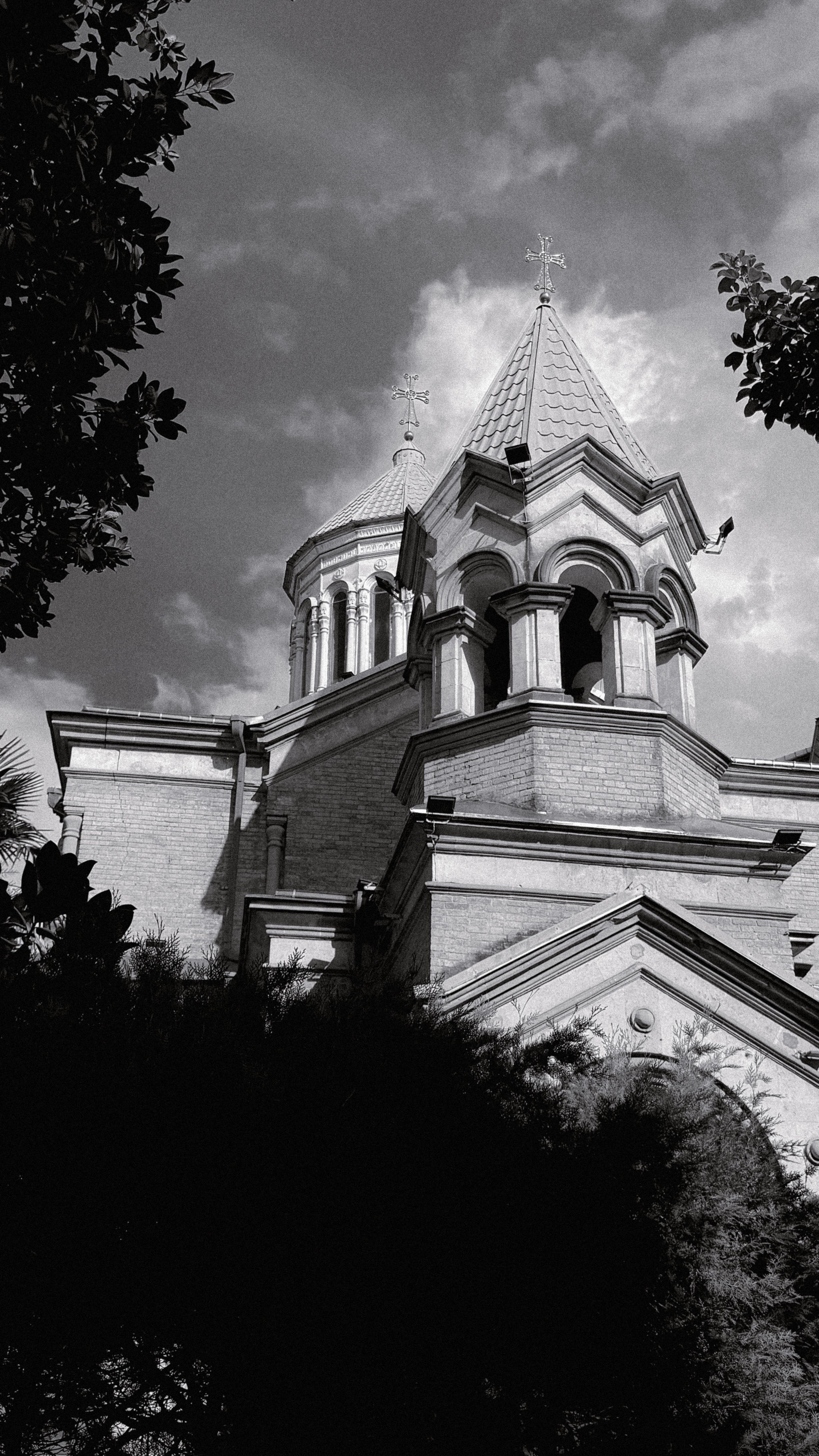 Black and white photo of a Gothic Revival church tower with dramatic clouds.