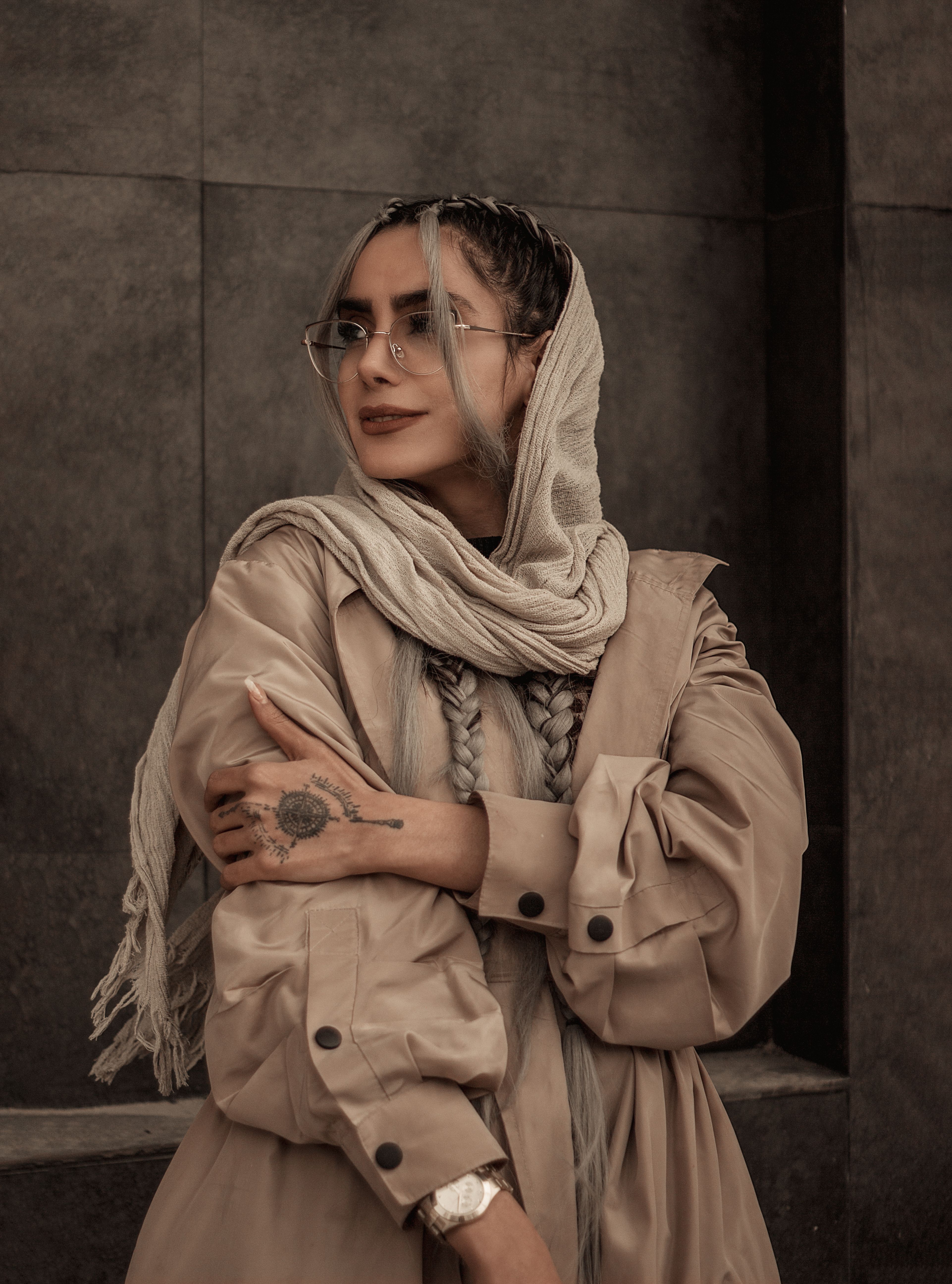 Stylish Middle Eastern woman posing gracefully in a beige outfit with headscarf in urban Kermanshah setting.