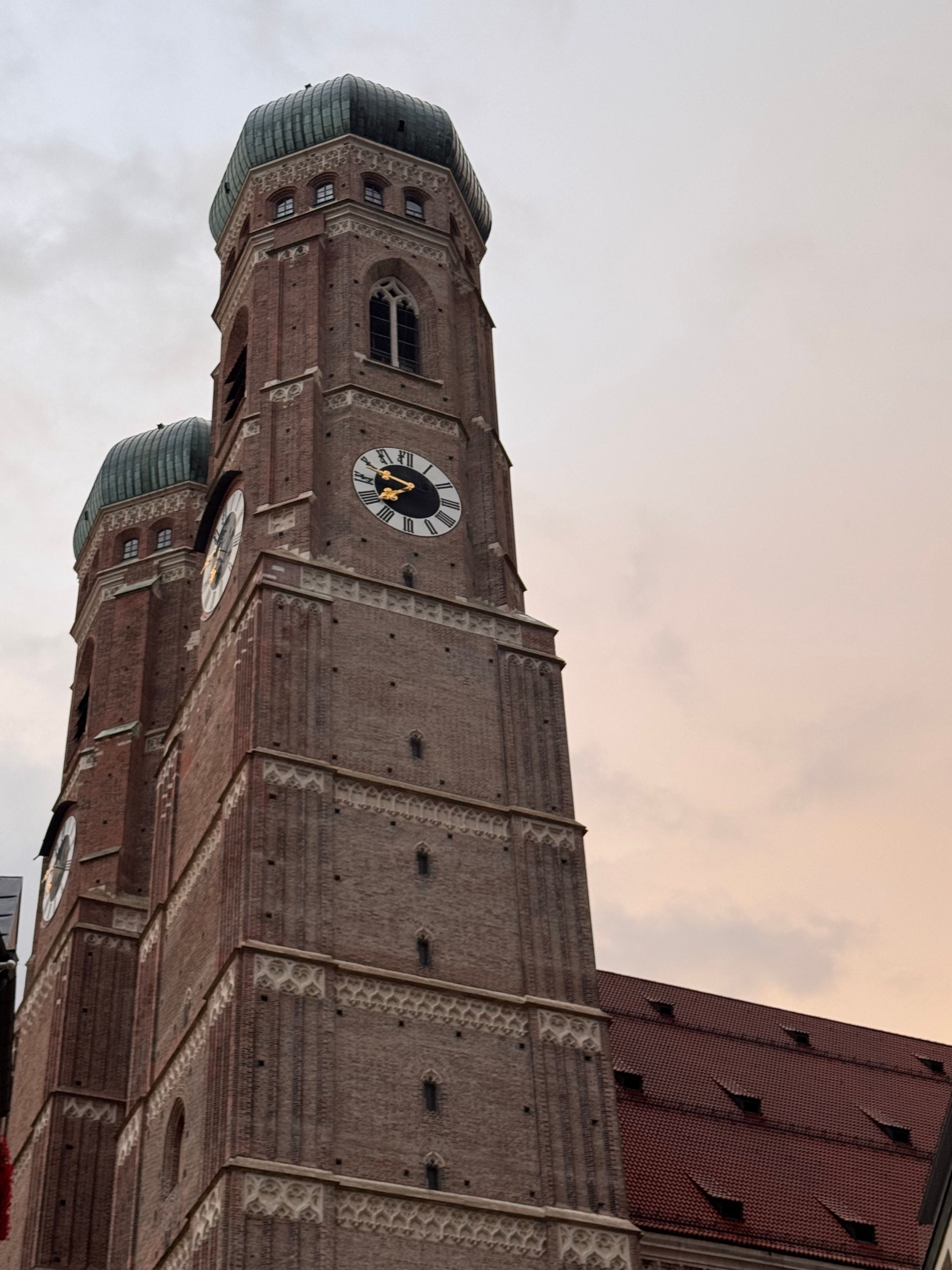 Scenic view of Munich's iconic Frauenkirche towers against a pastel evening sky.