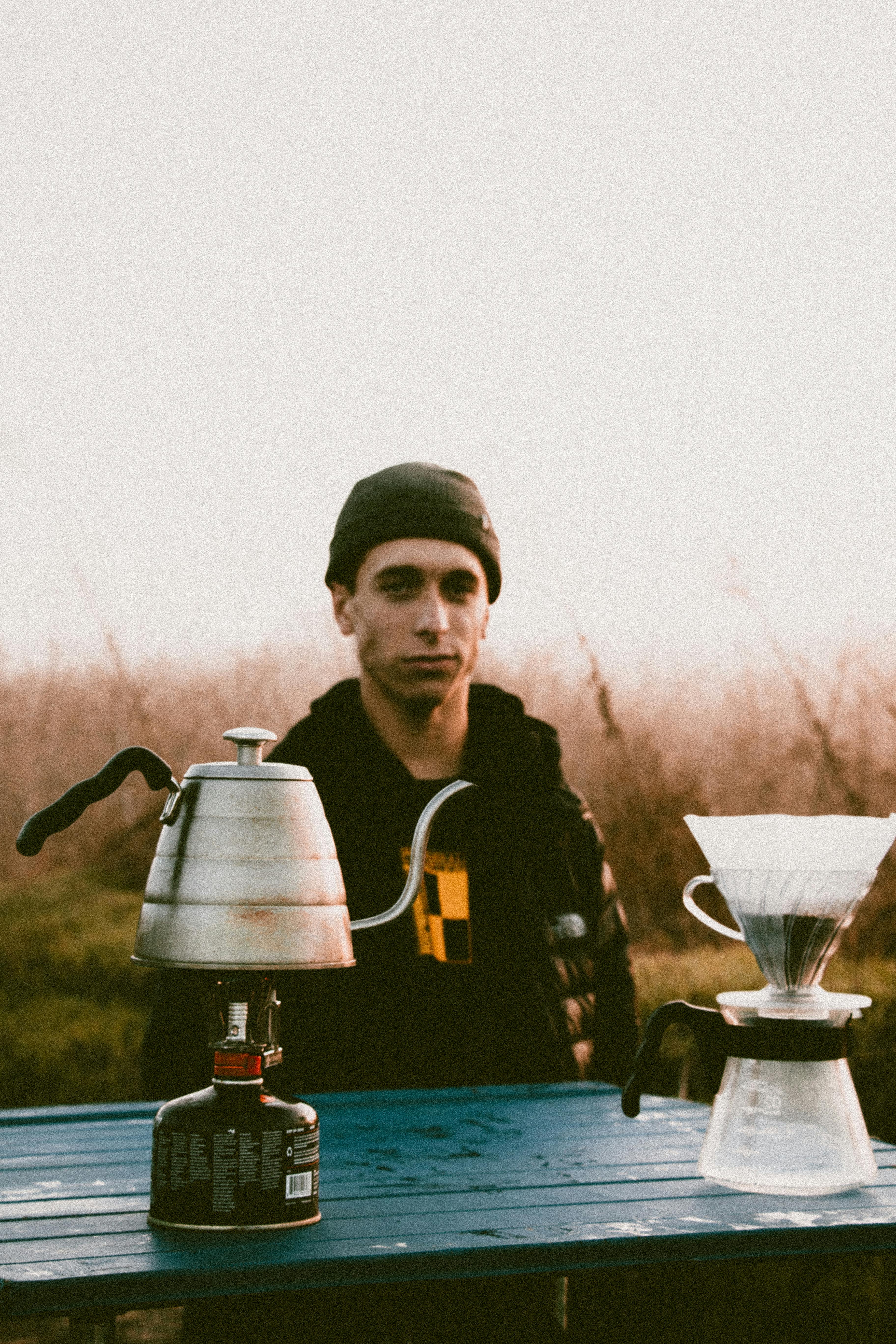 一名男子喜欢在户外用滴水装置和水壶煮咖啡，捕捉休闲时刻