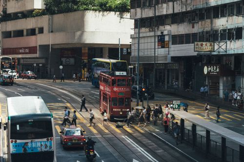 Free A vibrant street scene in Hong Kong featuring a classic red double-decker tram, surrounded by busy pedestrians and traffic. Stock Photo