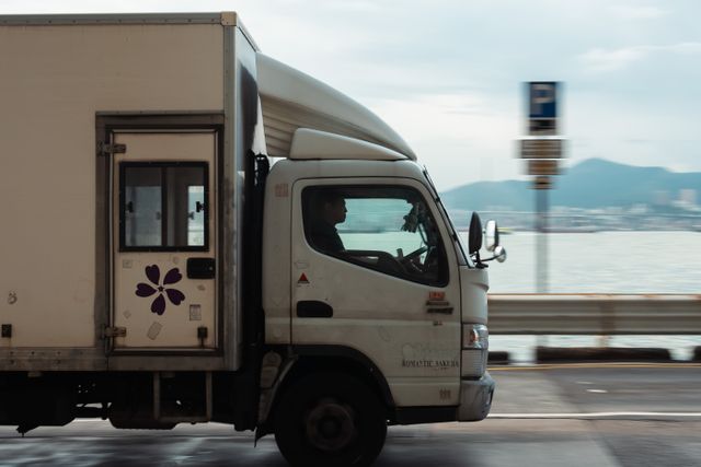 Camion de livraison sur une route côtière face à la montagne, transport de marchandises