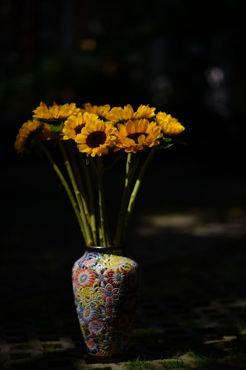 Free A bouquet of bright sunflowers in a decorative vase set against a dark background. Stock Photo