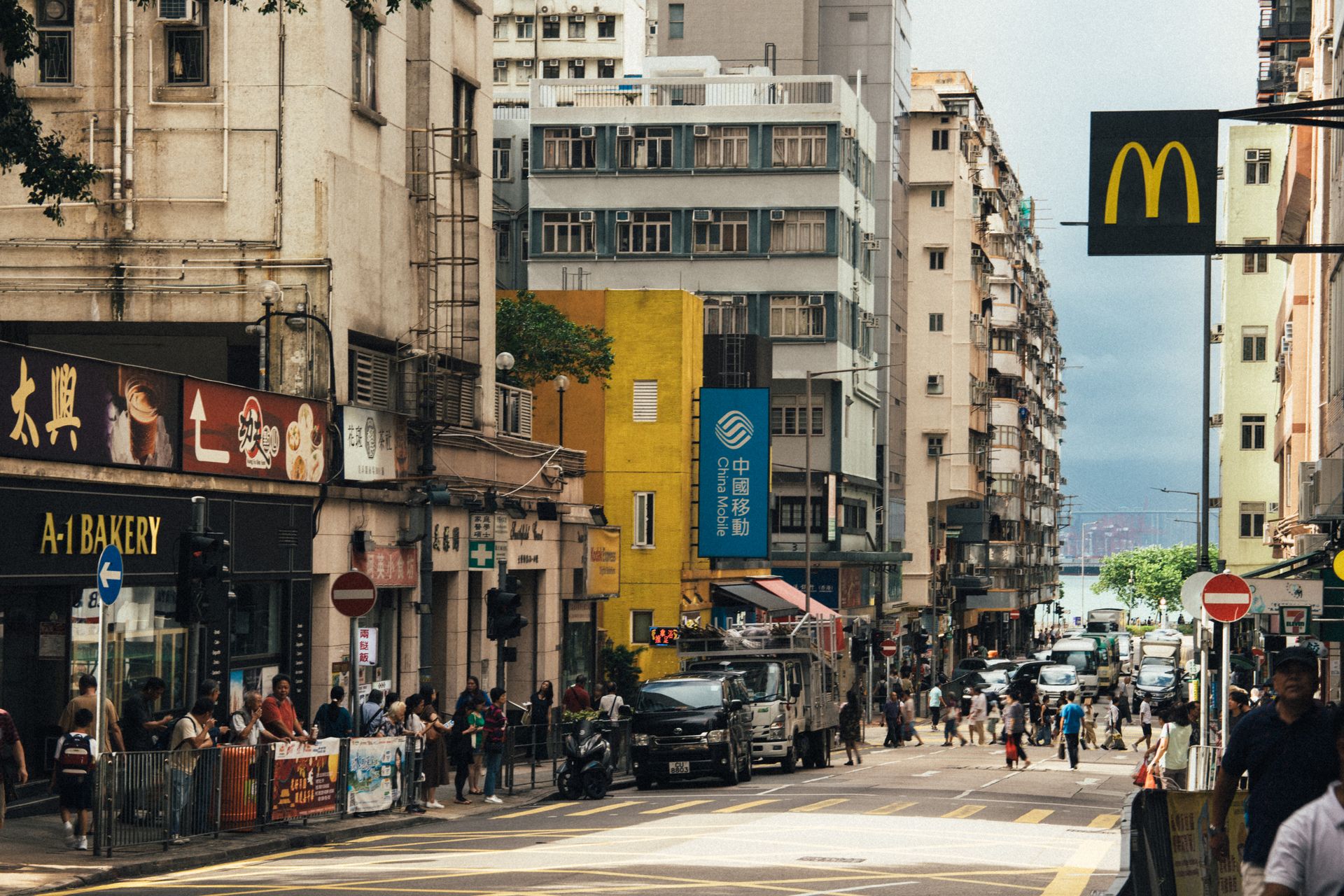Vibrant street scene in Hong Kong featuring shops, signs, and a busy pedestrian crossing.