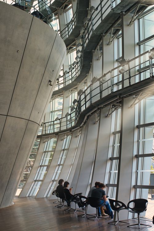 Free People seated in a stunning modern architectural space with curved glass walls and sleek design. Stock Photo