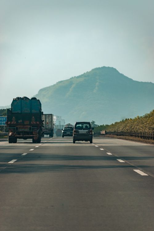 Free Vehicles driving on a highway with a backdrop of foggy hills in Navi Mumbai, India. Stock Photo