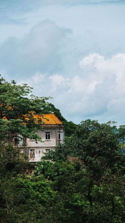 Free A picturesque house with a yellow roof surrounded by greenery against a dramatic sky in Hong Kong. Stock Photo