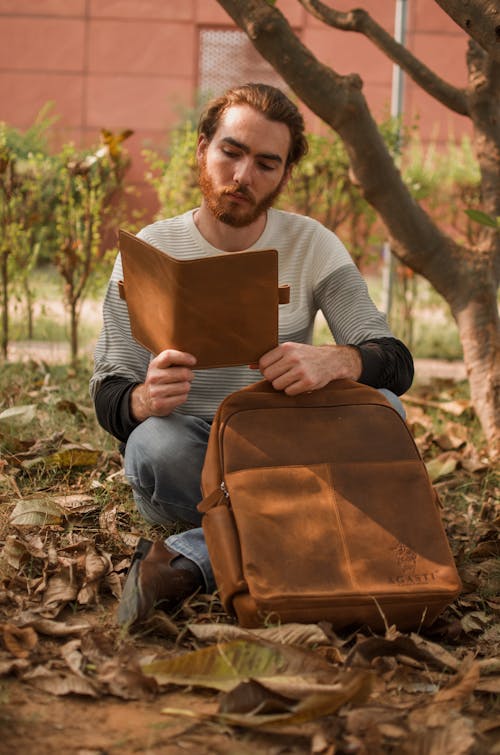 Селективный фокус фотографии человека, читающего книгу у дерева