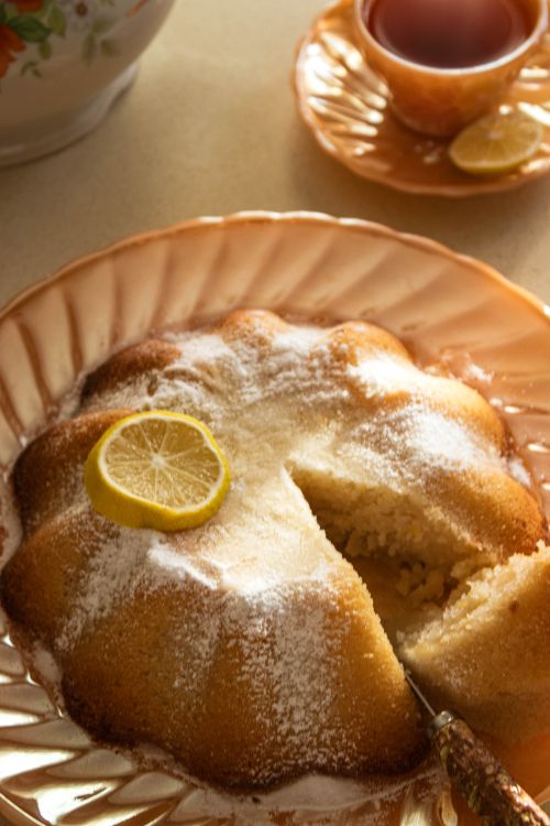 Free Delicious lemon-flavored tea cake topped with icing sugar and lemon slice, perfect for teatime. Stock Photo