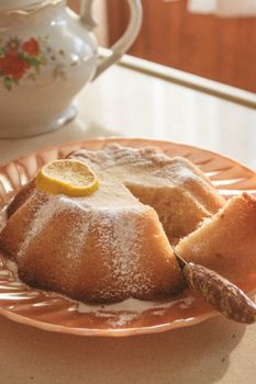 A fresh lemon bundt cake with powdered sugar served on a vintage plate, creating a cozy, nostalgic vibe.