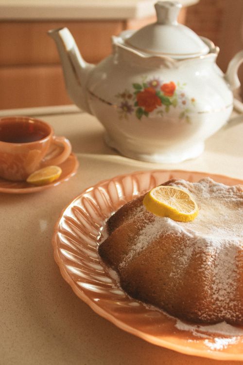Free Cozy vintage tea set with powdered sugar lemon bundt cake and floral teapot on a countertop. Stock Photo