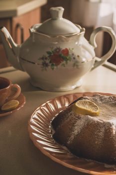 Warm afternoon tea with a ceramic teapot and lemon cake in a cozy home setting.