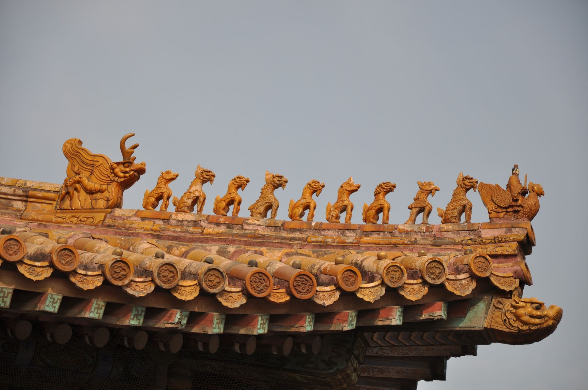 Close-up of a traditional Chinese roof featuring intricate decorative figurines under a blue sky.