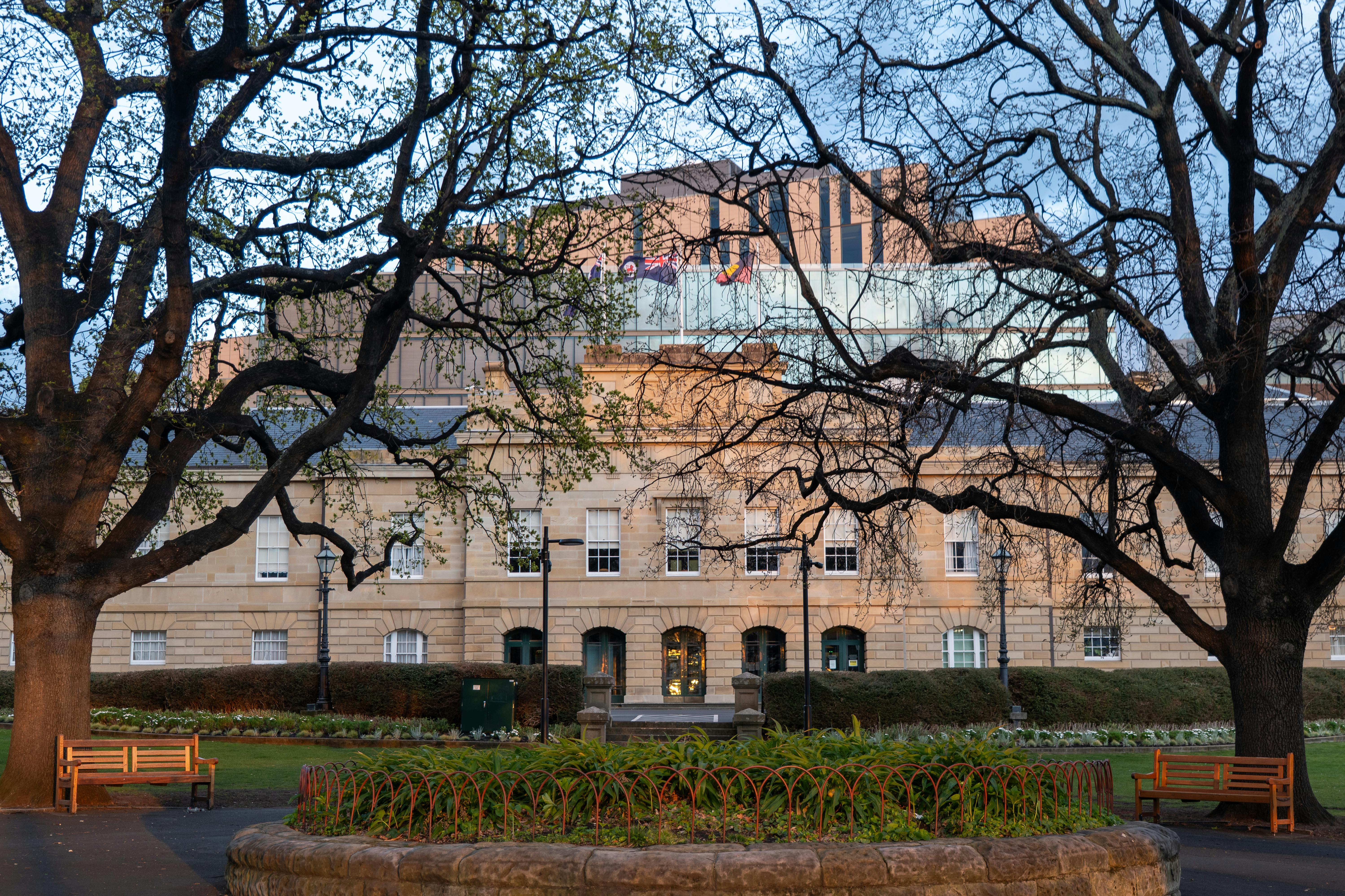 A beautiful scene of Hobart's historic architecture framed by lush trees at dusk, Tasmania, Australia.