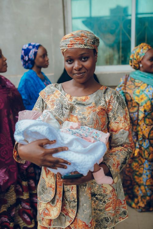 Free A Nigerian woman in traditional attire lovingly holds a baby, capturing the essence of cultural heritage and family joy. Stock Photo