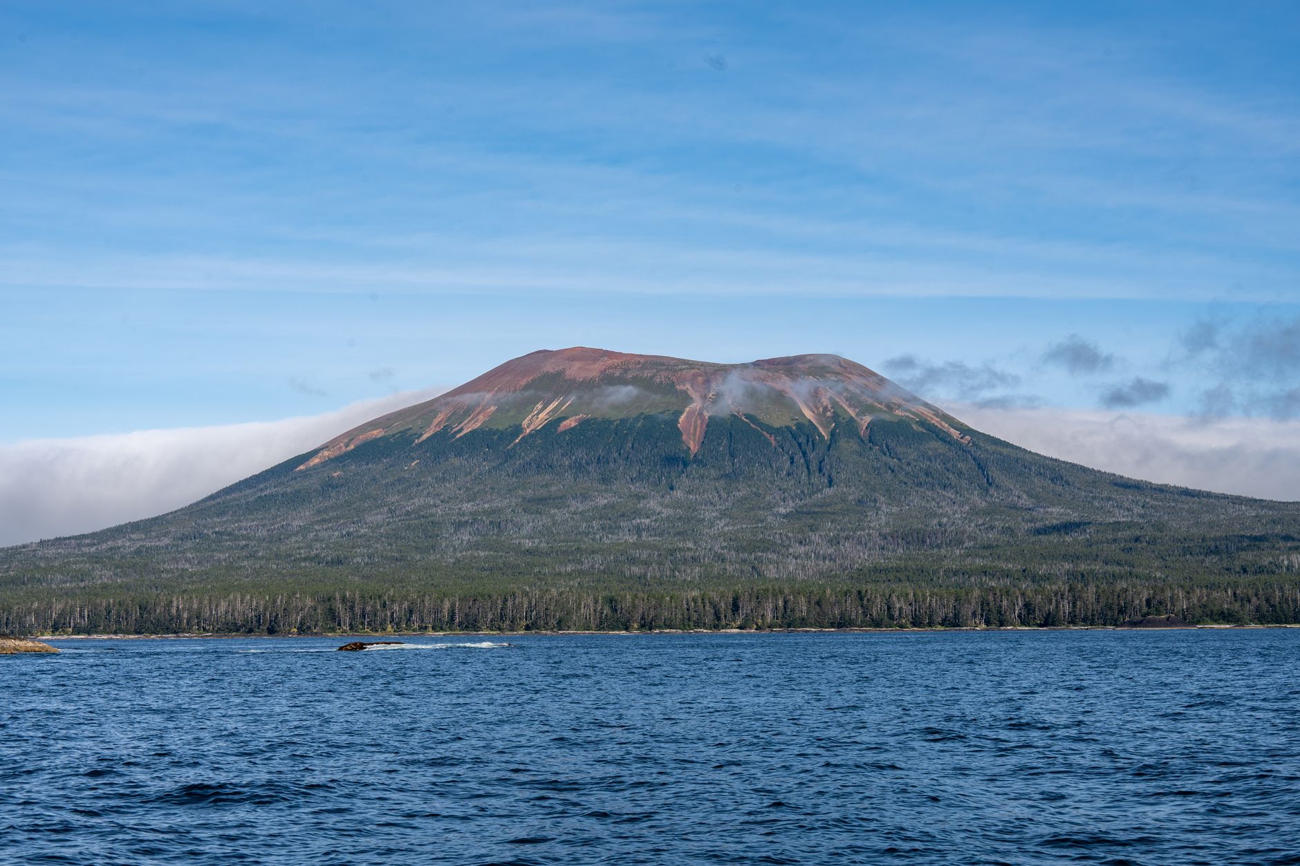 Stunning view of a dormant volcano surrounded by ocean and forest in Sitka, Alaska.