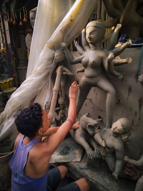 Free Artisan shaping a clay Durga idol in a Kolkata workshop, capturing cultural craftsmanship. Stock Photo