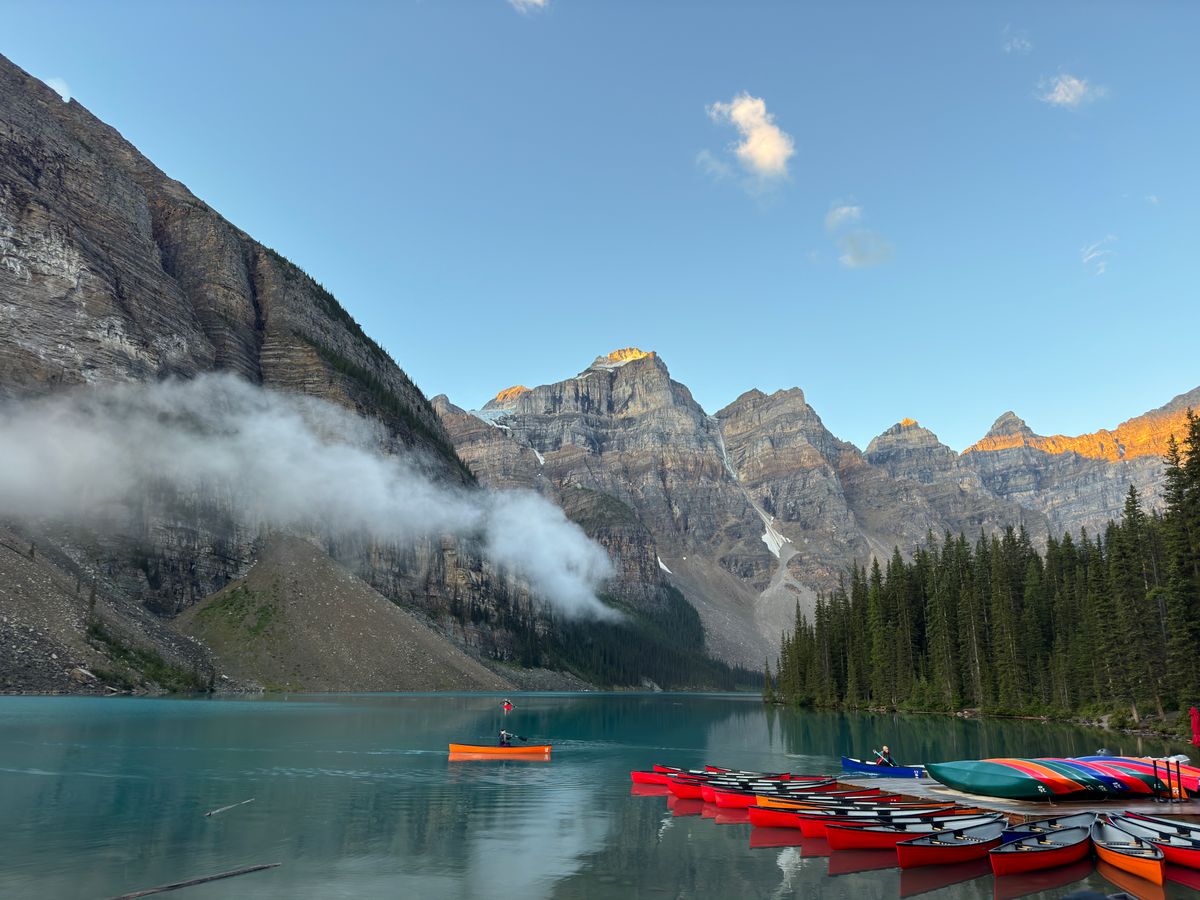 Colorful canoes on Moraine Lake with stunning mountain backdrop in Banff National Park, Canada.