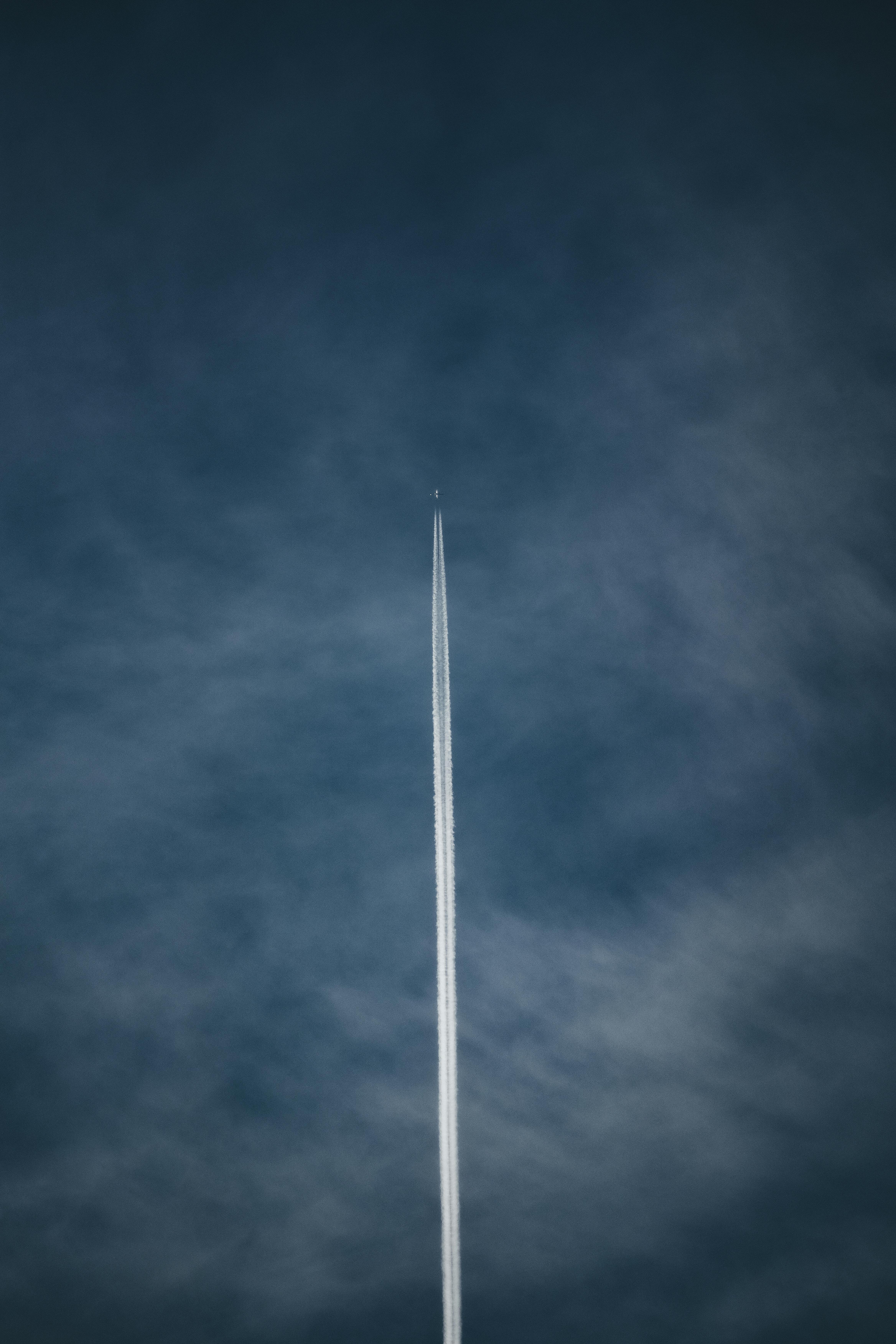 grátis Um avião a jato deixa uma longa trilha de condensação enquanto voa alto em um céu azul claro, misturando-se com nuvens finas. Foto profissional
